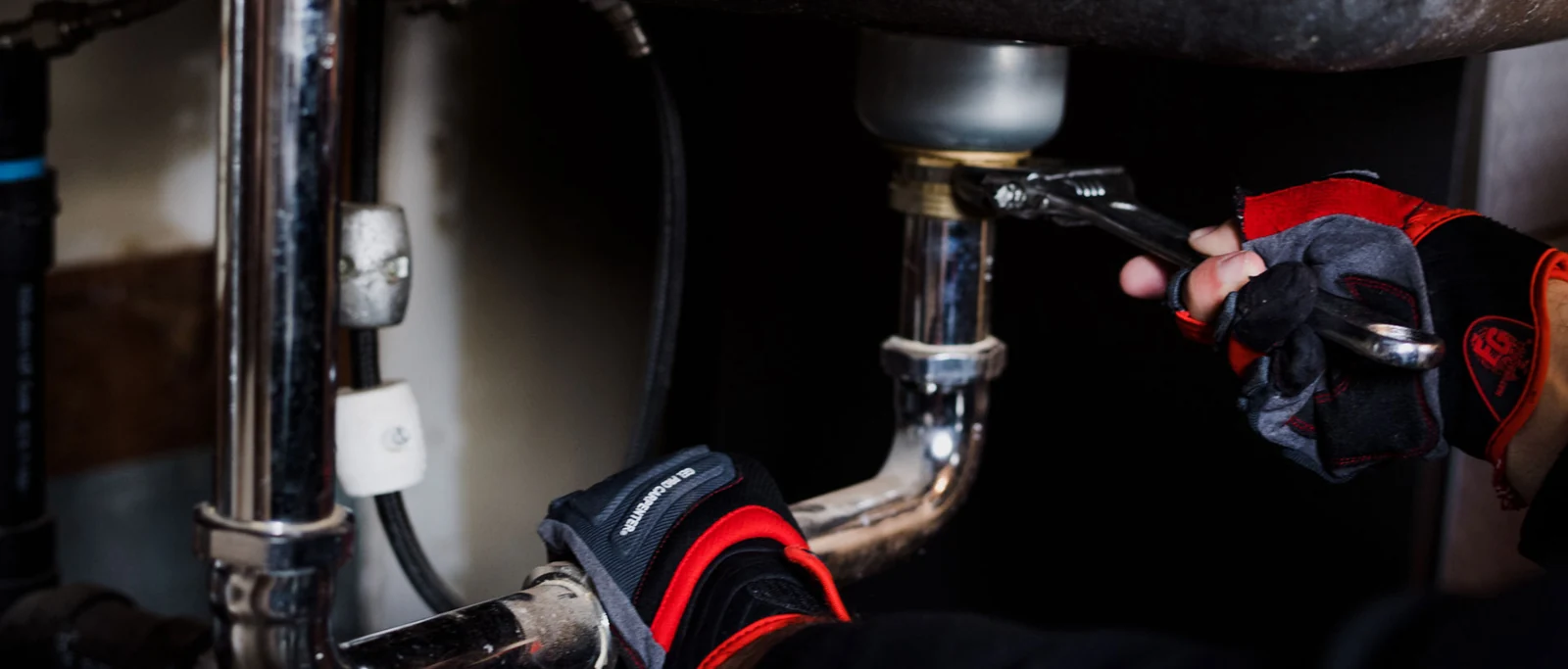 Hands working on sink plumbing